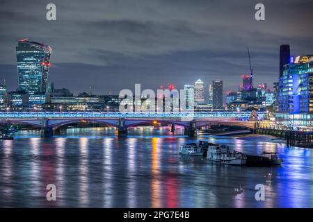 Un paesaggio urbano notturno di Londra che include Blackfriars Bridge e il fiume Tamigi con gli edifici della città di Londra e i Docklands dietro. Foto Stock