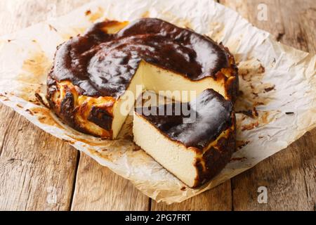 Tradizionale cheesecake basca bruciato su un tavolo rustico di legno closeup sulla carta pergamena. Orizzontale Foto Stock