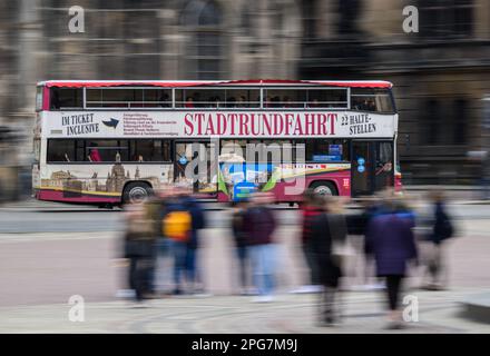 Dresda, Germania. 21st Mar, 2023. Un autobus rosso a due piani del tour della città viaggia la mattina nella città vecchia sopra la Theaterplatz. (Ripresa con tempo di esposizione lungo) Credit: Robert Michael/dpa/Alamy Live News Foto Stock