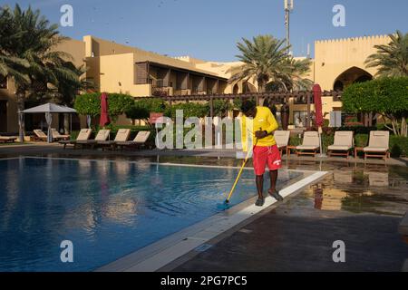 Un bagnino operaio immigrato maschio pulisce la piscina al mattino. Al Tilal Liwa Hotel desertico resort vicino Abu Dhabi, Emirati Arabi Uniti Foto Stock