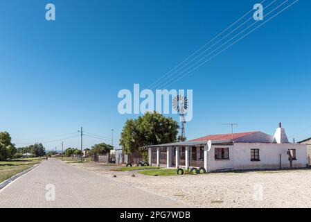 Campbell, Sudafrica - 24 febbraio 2023: Una scena di strada, con vecchie case, a Campbell. È visibile un mulino a vento Foto Stock