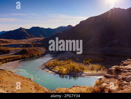 La confluenza di due fiumi di montagna Chuya e Katun sotto una roccia all'ombra dei raggi del sole. Foto Stock