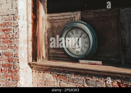 Un classico orologio a pendolo antico montato su una parete di mattoni in un vecchio edificio Foto Stock