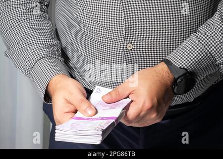 Un uomo d'affari di successo che conta un sacco di euro denaro contante banconote. Conteggio delle banconote in euro, finanza, corruzione, concetti di investimento, focalizzazione selettiva Foto Stock