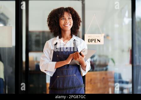 Startup successo piccolo bello americano africano proprietario sme bellezza ragazza stand con tablet in caffetteria ristorante, imprenditore venditore business Foto Stock