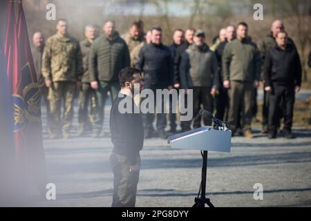 Moschun, Ucraina. 21st Mar, 2023. Il presidente ucraino Volodymyr Zelenskyy rappresenta l'inno nazionale durante una cerimonia presso il sito commemorativo degli Angeli della Vittoria, 21 marzo 2023 a Moschun, Kyiv Oblast, Ucraina. Credit: Foto piscina/Ufficio stampa presidenziale ucraino/Alamy Live News Foto Stock