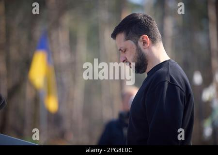 Moschun, Ucraina. 21st Mar, 2023. Il presidente ucraino Volodymyr Zelenskyy rappresenta l'inno nazionale durante una cerimonia presso il sito commemorativo degli Angeli della Vittoria, 21 marzo 2023 a Moschun, Kyiv Oblast, Ucraina. Credit: Foto piscina/Ufficio stampa presidenziale ucraino/Alamy Live News Foto Stock