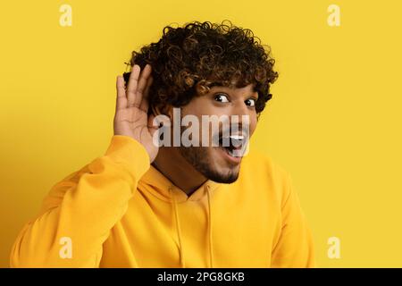 Ragazzo indiano eccitato che tiene la mano accanto all'orecchio Foto Stock