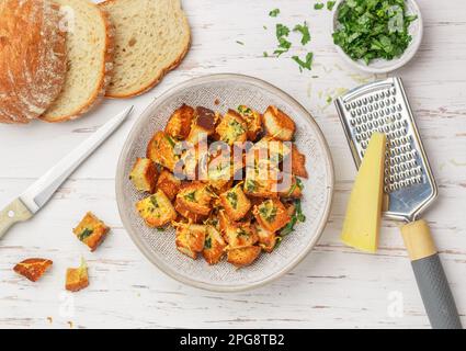 Crostini con erbe, aglio e formaggio di pane bianco o baguette. Servito per insalata o zuppa. Messa a fuoco selettiva, vista dall'alto Foto Stock