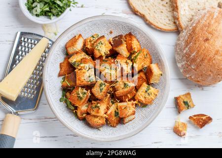 Crostini con erbe, aglio e formaggio di pane bianco o baguette. Servito per insalata o zuppa. Messa a fuoco selettiva, vista dall'alto Foto Stock