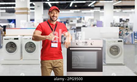 Venditore con elettrodomestici sorridenti e che punta verso un forno all'interno di un negozio Foto Stock