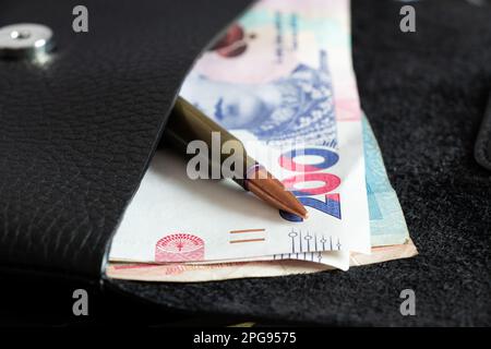 200 l'hryvnia e una pallottola giacciono in un portafoglio sul tavolo, armi e denaro Foto Stock