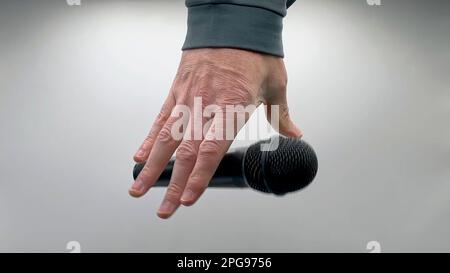 Uomo caucasico che cade la sequenza di microfoni - prestazioni popolari microfono dinamico tutto nero - solo mani - sfondo bianco - concetto semplice Foto Stock