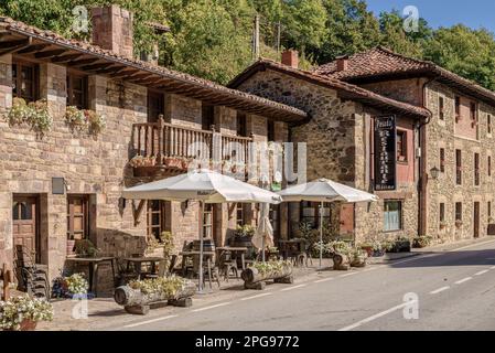 Maximo ristorante inn edificio, terrazza con tavoli, sedie e ombrelloni sulla strada nella città di Espinama, comune di Camaleño, Cantabria Foto Stock