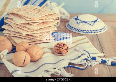 Concetto di celebrazione della Pasqua. Matzah, kosher rosso e noce. Tradizionale matzah di pane ebraico rituale, kippah e tallit su vecchio sfondo di legno. Passo Foto Stock