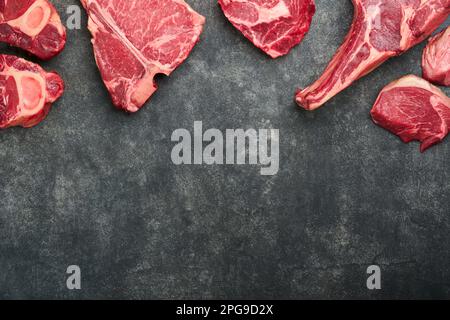 Bistecche di prima qualità. Varietà di carni fresche di prima qualità angus nero bistecche T-bone, New York, Ribeye, Striploin, Tomahawk su sfondo nero o grigio pietra. Imposta Foto Stock