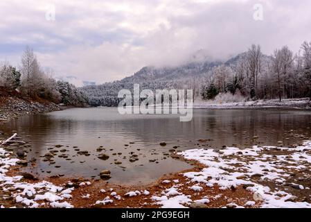 La neve bianca si trova sulla pittoresca spiaggia di pietra vicino alla foresta, vicino alla baia del fiume Katun, sulle montagne Altai in Siberia. Foto Stock