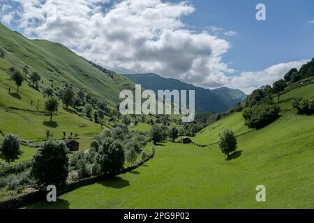Prati e casette rustiche in pietra nella bella valle verde, Valles pasiegos, Cantabria, Spagna Foto Stock