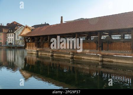 Thun, Svizzera, 13 febbraio 2023 storico ponte di legno vecchio attraverso il fiume Aare sul lungomare nel centro della città Foto Stock