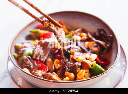 Piatto cinese fritto in padella con manzo a dadini, verdure e arachidi cotte in padella. Foto Stock