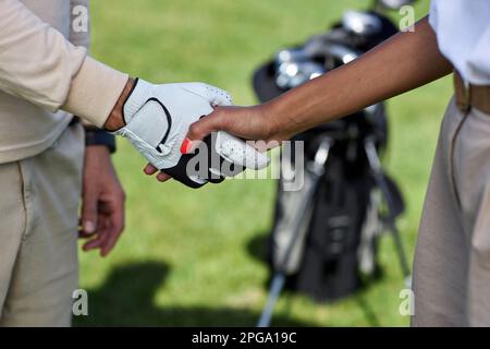 Primo piano di due giocatori di golf che scuotono le mani dopo la partita all'aperto Foto Stock