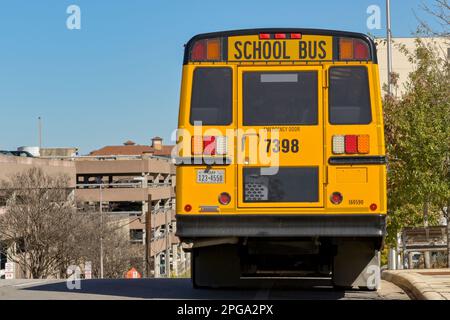 Austin, Texas, USA - Febbraio 2023: Vista posteriore di un autobus giallo scuola parcheggiato sul fronte di una collina su una strada cittadina Foto Stock