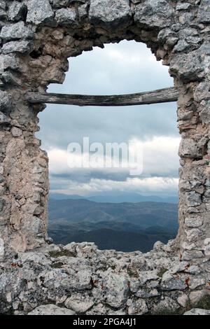 La tempesta nella valle, vista attraverso il gash del muro in rovina, Rocca Calascio, l'Aquila, Abruzzo, Italia Foto Stock