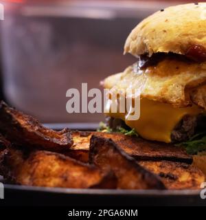 Hamburger servito con patatine fritte primo piano sfondo sfocato Foto Stock