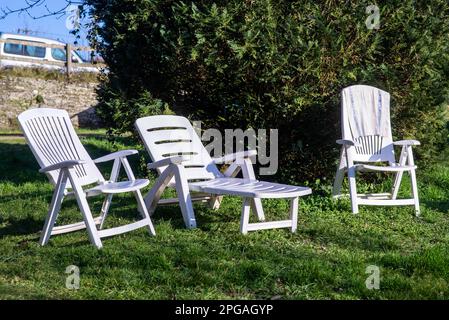 Lettini vuoti sull'erba nel cortile della casa. Luoghi per rilassarsi vicino a alberi verdi. Relax. Foto Stock