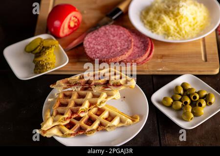 Sandwich di waffle con salame, olive, formaggio, pomodoro. waffle pizza, piffé. Foto Stock