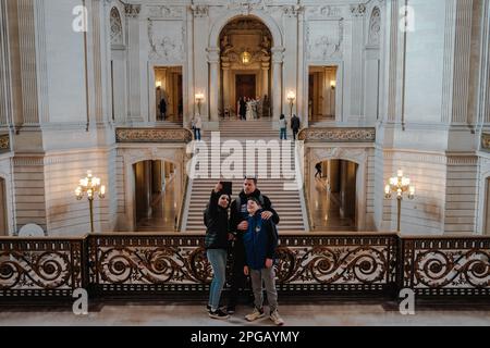 California, San Francisco, Stati Uniti. 20th Mar, 2023. Le persone scattano foto davanti alla grande scalinata all'interno del Municipio, che è stato splendidamente restaurato e riportato alle sue condizioni originali. La scala presenta ringhiere ornate, intarsi intricati e uno stupefacente lampadario sospeso dal soffitto. Dopo due anni di lavori di ristrutturazione, l'iconico municipio di San Francisco ha finalmente riaperto le sue porte al pubblico dal giugno 2021. Il progetto da $550 milioni di dollari mirava a ripristinare gli elementi storici dell'edificio e a modernizzarlo per soddisfare le esigenze del 21st.The progetto coinvolse il resto Foto Stock