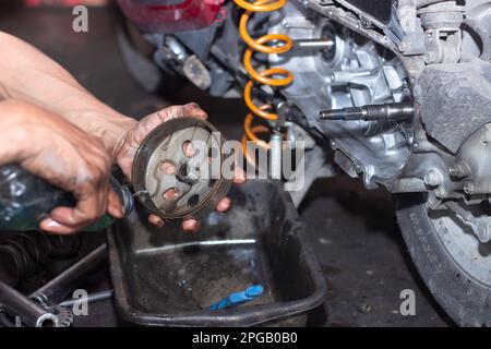 Il meccanico della motocicletta controlla le condizioni del sistema di trasmissione automatica o del sistema della frizione dello scooter in officina. Concetto di riparazione e manutenzione della motocicletta Foto Stock