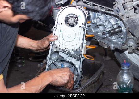 Il meccanico della motocicletta controlla le condizioni del sistema di trasmissione automatica o del sistema della frizione dello scooter in officina. Concetto di riparazione e manutenzione della motocicletta Foto Stock