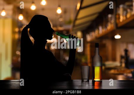 Dipendenza da alcol. Silhouette di donna che beve birra al bar Foto Stock