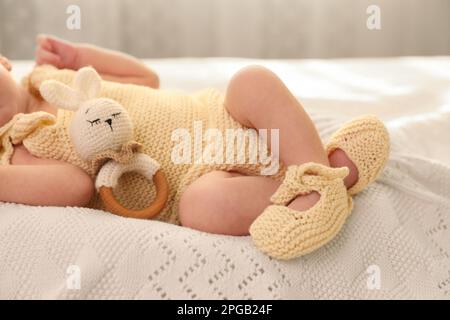 Neonato con giocattolo su plaid a maglia, primo piano Foto Stock