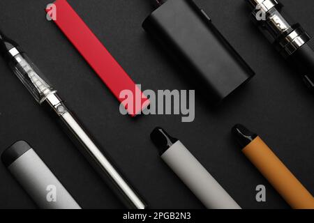 Molti dispositivi elettronici per fumare su sfondo nero, a posa piatta Foto Stock