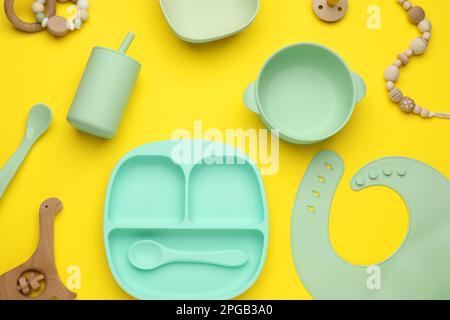 Set di stoviglie in plastica e accessori per bambini su sfondo giallo, piatto Foto Stock