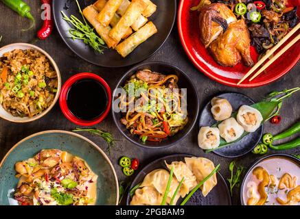 Un assortimento di piatti Cinesi. Tagliatelle cinesi, riso fritto, gnocchi, anatra alla pechinese, dim sum, involtini primavera. Famosa cucina Cinese piatti sulla tavola. Parte superiore Foto Stock