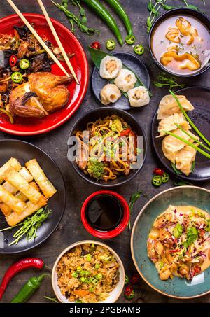 Un assortimento di piatti Cinesi. Tagliatelle cinesi, riso fritto, gnocchi, anatra alla pechinese, dim sum, involtini primavera. Famosa cucina Cinese piatti sulla tavola. Parte superiore Foto Stock