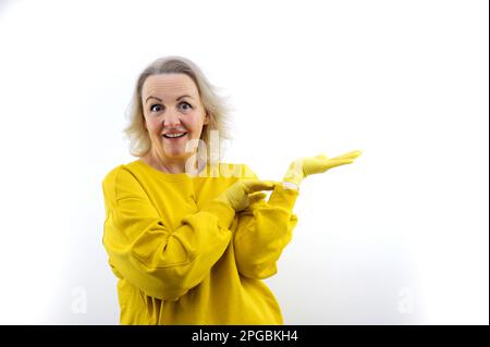 Donna di mezza età che indossa giallo in piedi su sfondo bianco isolato stupito e sorridente alla fotocamera mentre si presenta con la mano e puntando con il dito. Alta qualità Foto Stock