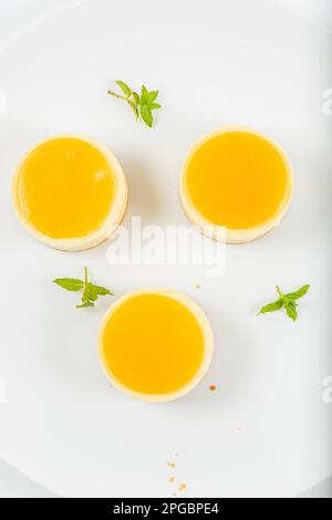 Cheesecake cremoso al mango piccolo con gelatina di mango e una base di briciole di grano integrale. Foto Stock