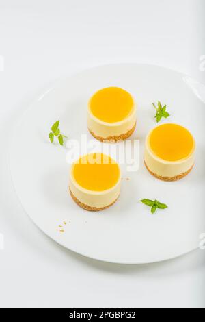 Cheesecake cremoso al mango piccolo con gelatina di mango e una base di briciole di grano integrale. Foto Stock