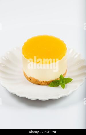 Cheesecake cremoso al mango piccolo con gelatina di mango e una base di briciole di grano integrale. Foto Stock