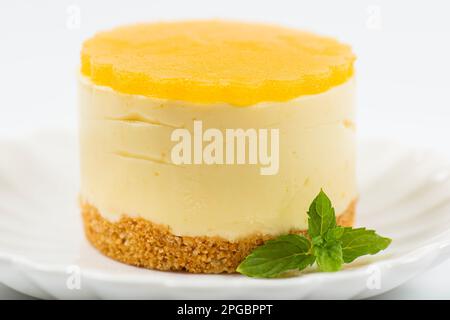 Cheesecake cremoso al mango piccolo con gelatina di mango e una base di briciole di grano integrale. Foto Stock