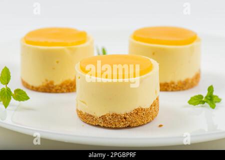 Cheesecake cremoso al mango piccolo con gelatina di mango e una base di briciole di grano integrale. Foto Stock