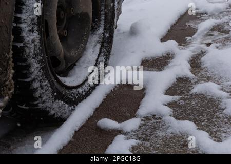 Traffico su strada invernale dopo la neve pesante. Primo piano di pneumatici invernali sulla vettura su strade innevate in città. Foto Stock