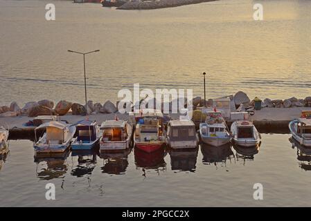 Barche da pesca nel porto al tramonto sul lungomare di Cesme, Turchia, dicembre 2022 Foto Stock