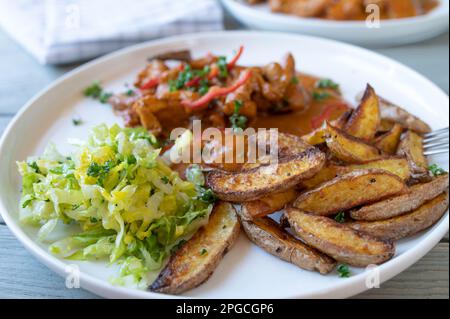 Spicchi di patate con pollo, salsa e insalata su un piatto Foto Stock