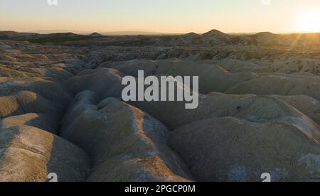 Spettacolare paesaggio di scoscese vallate rocciose con superficie irregolare e colline al tramonto Foto Stock