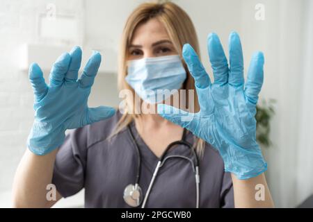 le mani del medico femminile nei guanti blu nitrile mostrano il dito Foto Stock